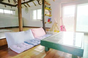 Una habitación acogedora con suelo de madera, un banco acolchado, una mesa con superficie de vidrio y una ventana con vistas.