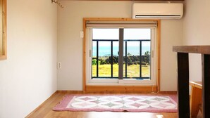 Une pièce dotée d’une grande porte-fenêtre coulissante donnant sur un balcon avec vue sur l’océan.