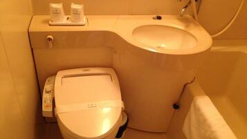 A bathroom with a toilet, bidet, and a sink.