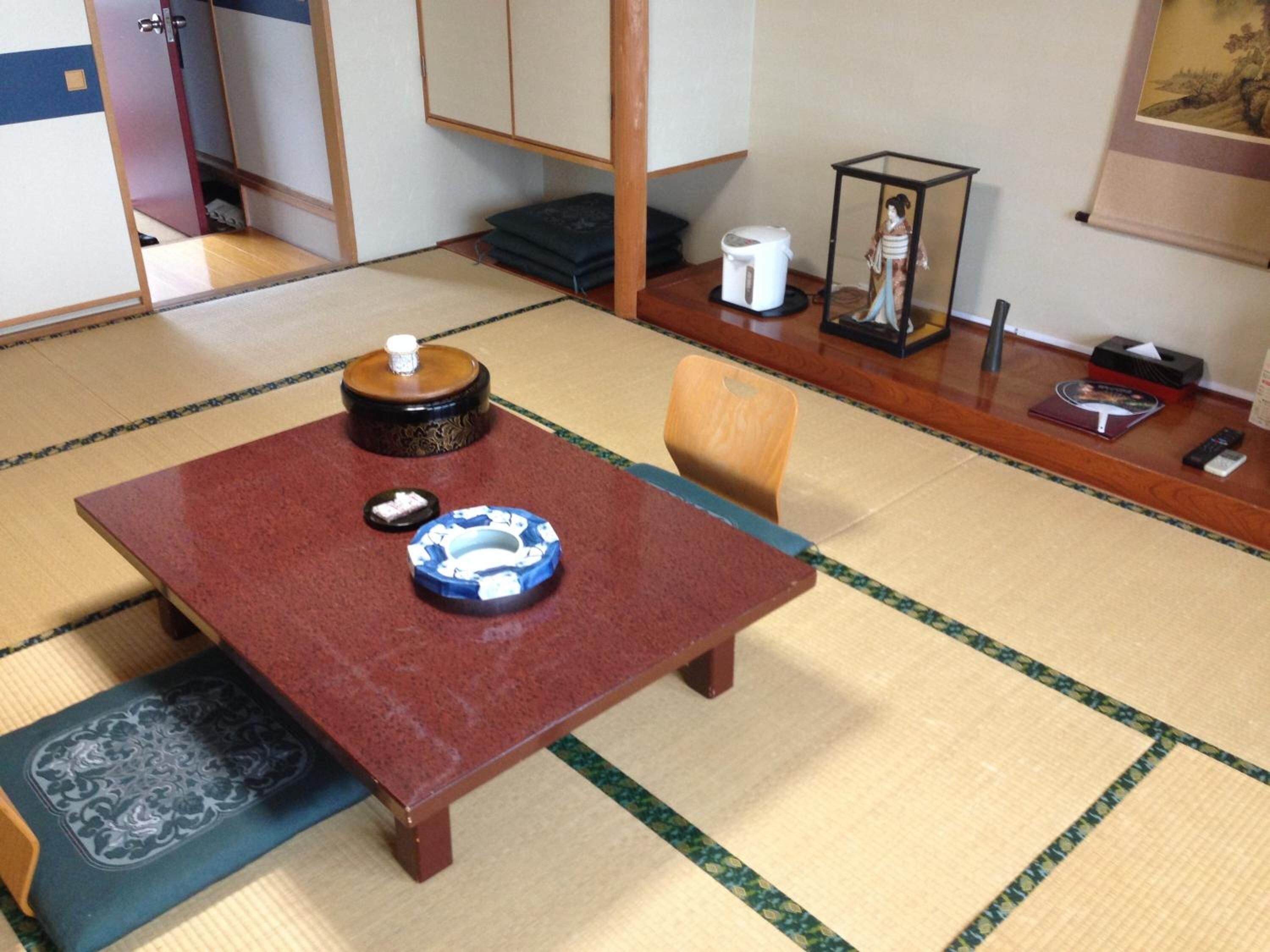 Una habitación con esteras de tatami, una mesa de madera baja, un juego de té japonés tradicional y un pequeño armario.