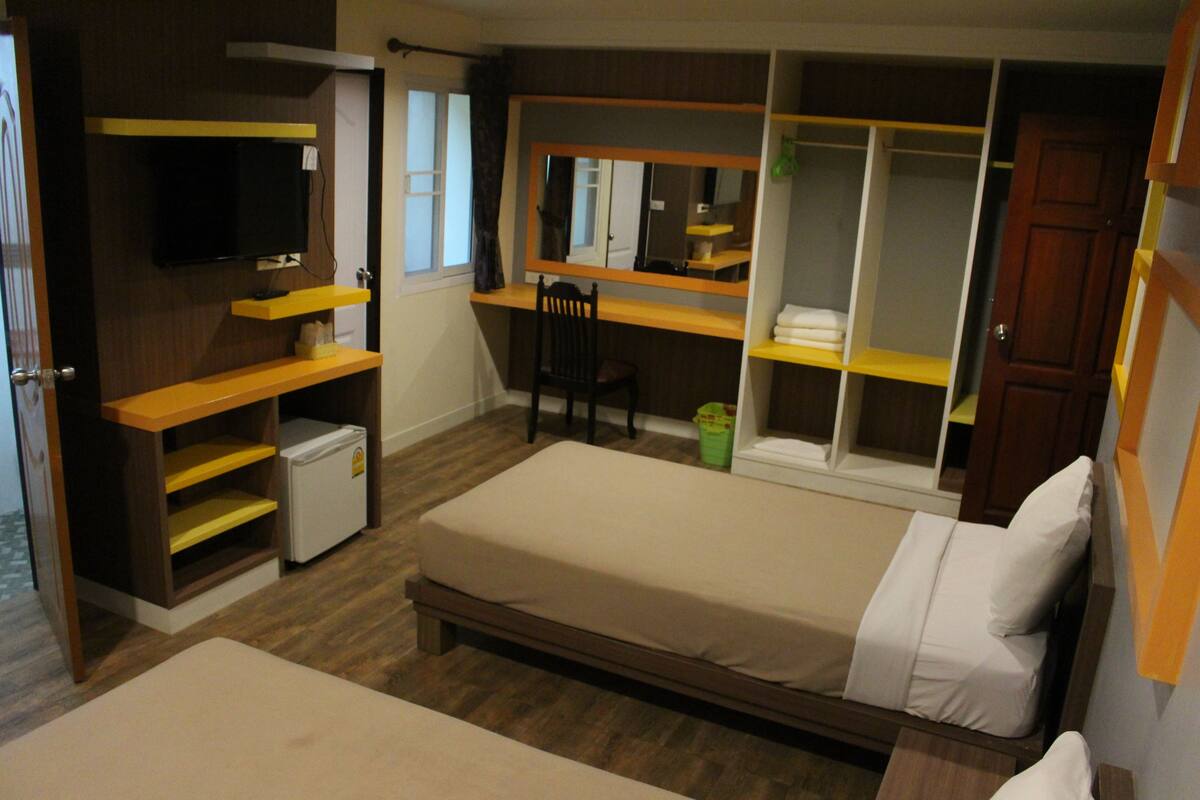 A bedroom with a bed, a desk, a chair, a television, and a wardrobe.