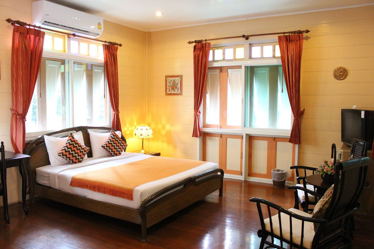 A hotel room with a bed, a desk, a chair, a TV, and a window with curtains.