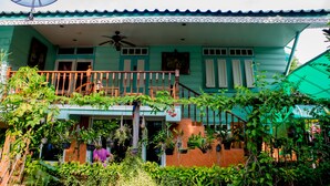 Ein zweigeschossiges Haus mit Balkon, Deckenventilator und Topfpflanzen.