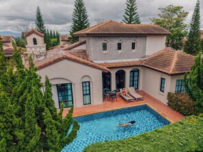 A large house with a swimming pool, surrounded by trees and other houses. - Mövenpick Resort Khao Yai (Pak Chong)