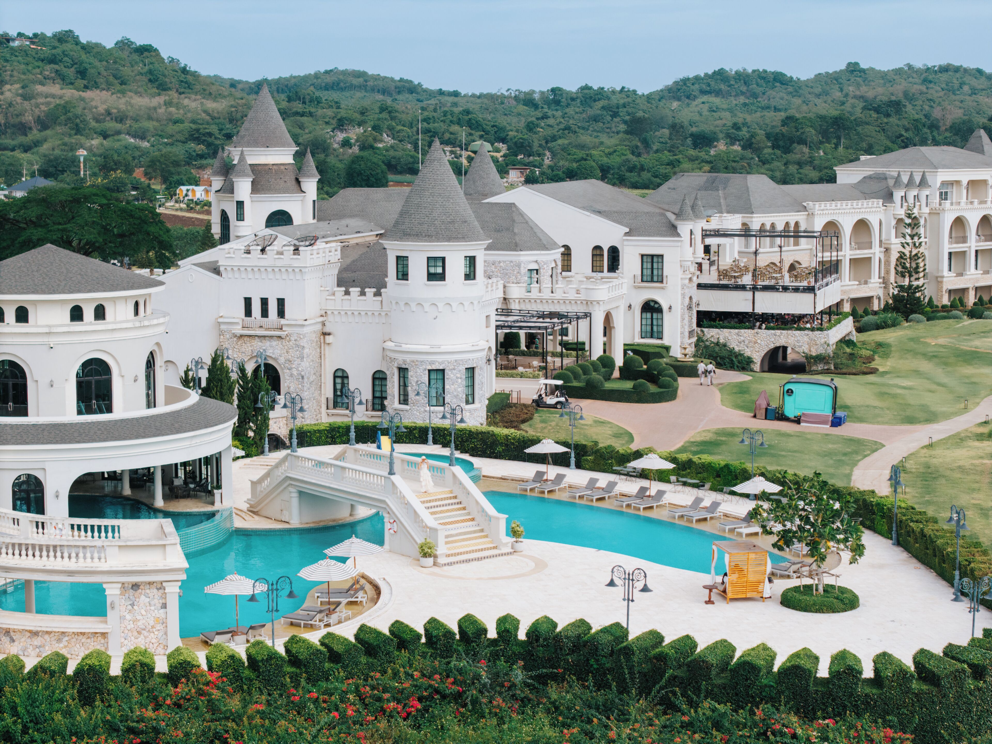 A resort with a large pool, multiple buildings, and a golf course.