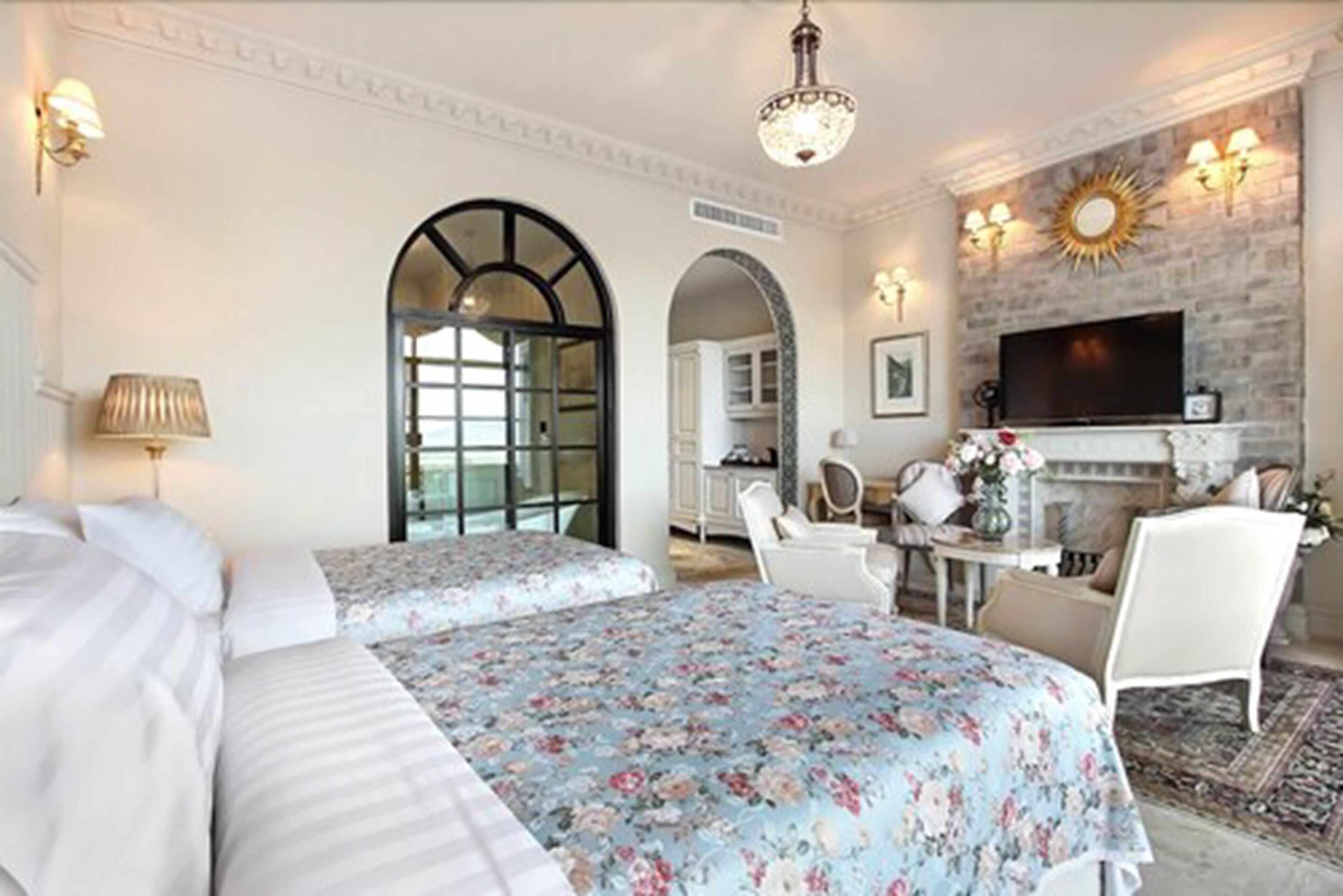 Une chambre d’hôtel avec deux lits, une cheminée, une télévision et un coin repas comprenant une table et des chaises.