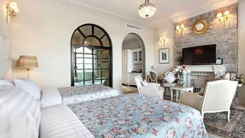 Une chambre d’hôtel avec deux lits, une cheminée, une télévision et un coin repas comprenant une table et des chaises.