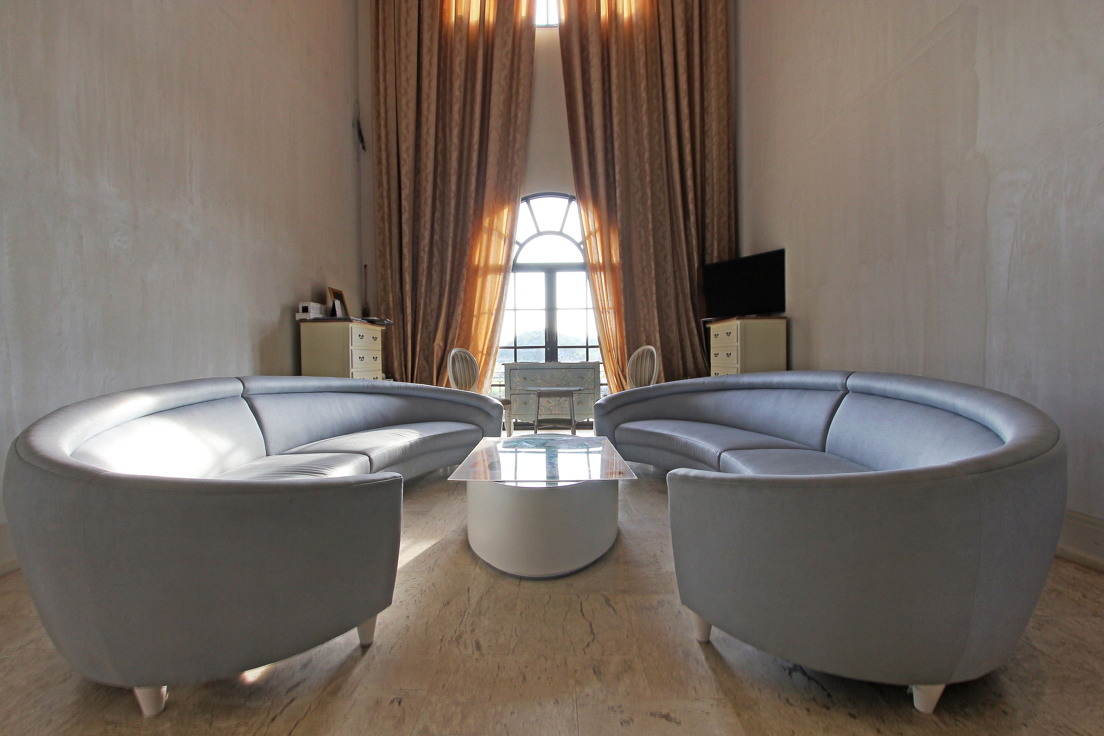 A modern living room with a curved sofa set, a central coffee table, and a television on a stand.