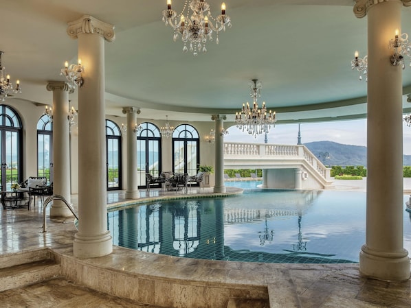 A luxurious indoor pool area with marble flooring, large windows, and elegant chandeliers. - Mövenpick Resort Khao Yai (Pak Chong)