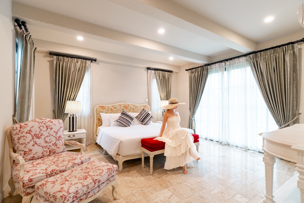 Une chambre d’hôtel avec un lit, une chaise, une table et des rideaux.