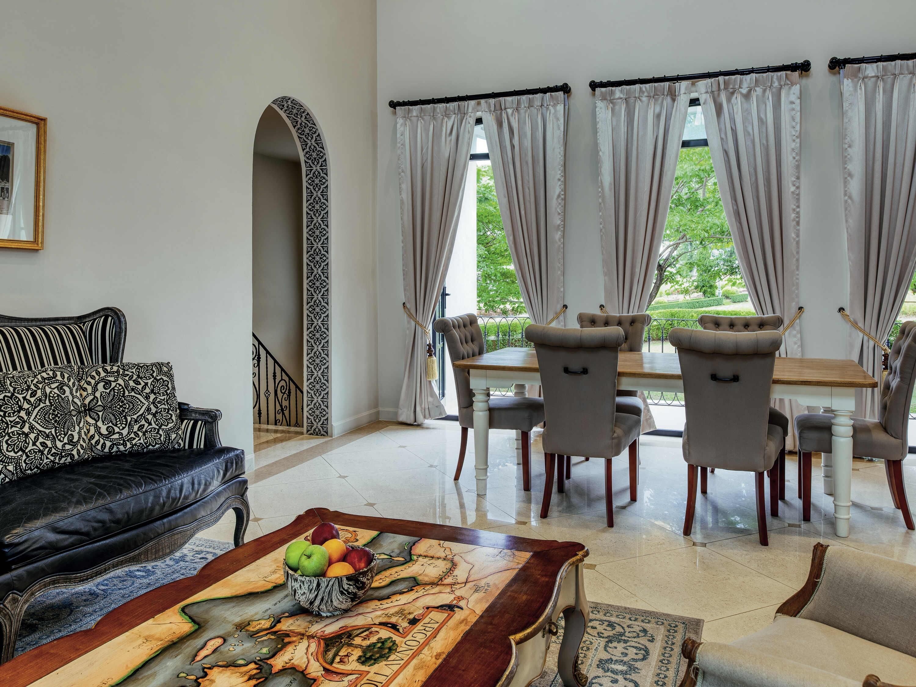 A dining area with a table and chairs, a sofa, and a decorative rug.