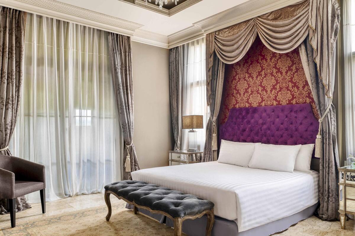 A spacious bedroom with a large bed, a tufted headboard, and a bench.