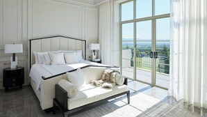 Une chambre spacieuse avec un grand lit, un coin salon et un balcon offrant une vue agréable.