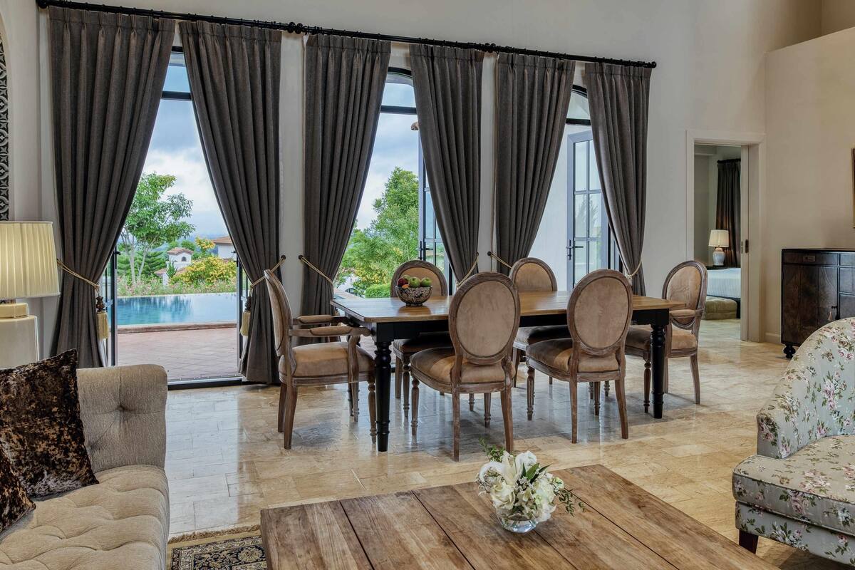 A dining area with a table and chairs, a coffee table with a vase, and a sofa.