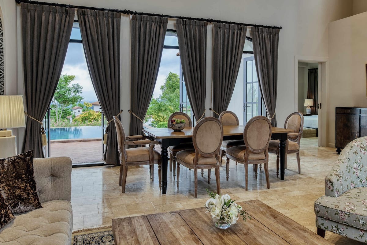 A dining area with a table and chairs, a coffee table with a vase, and a sofa.
