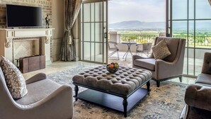 A spacious living room with a fireplace, a television, and a balcony with a view of the countryside. - Mövenpick Resort Khao Yai (Pak Chong)