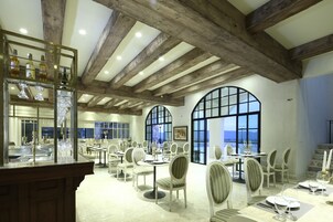 Un restaurante con vigas de madera, ventanas amplias y mesas dispuestas para comer.