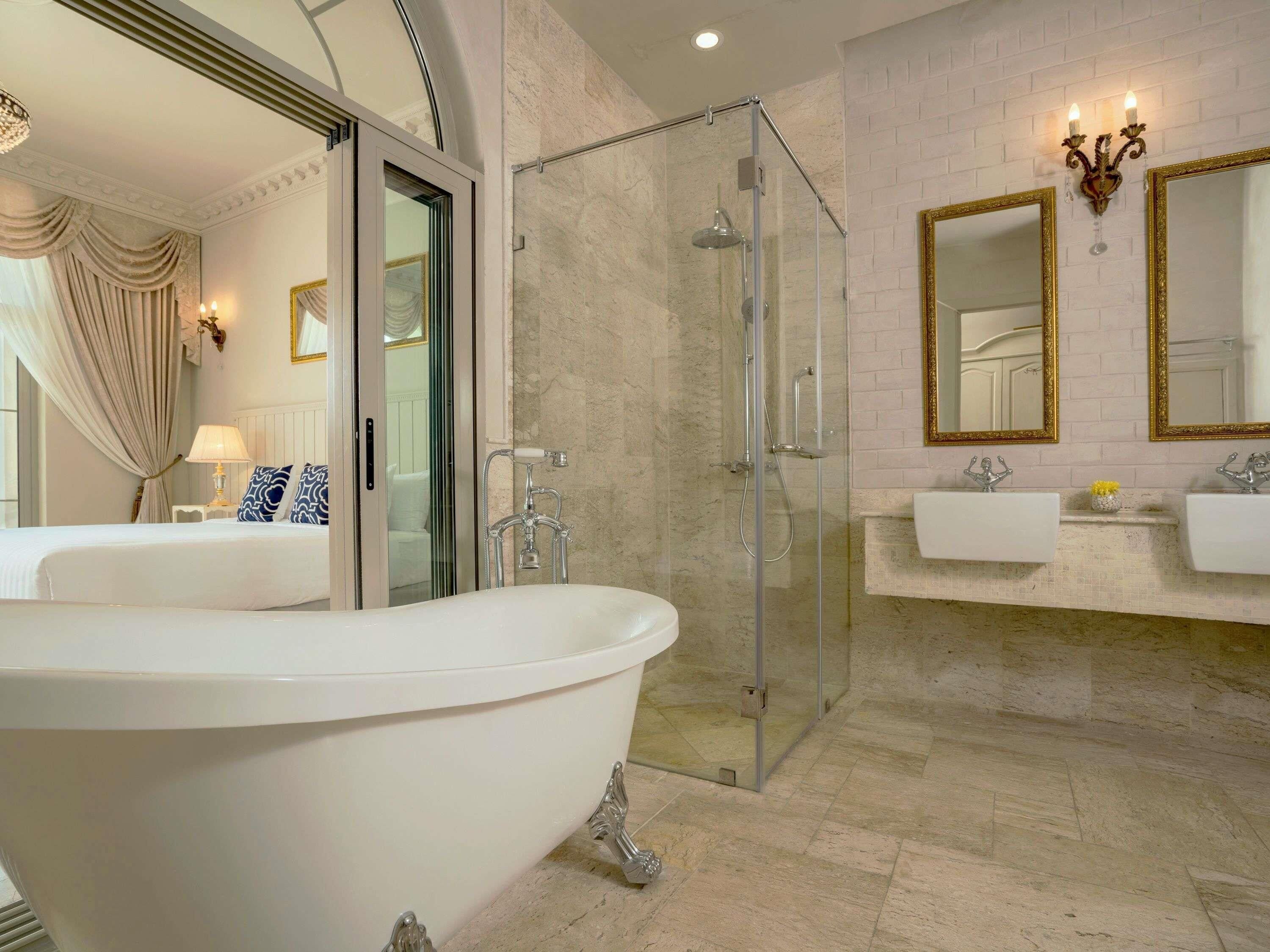 A bathroom with a freestanding bathtub, a glass-enclosed shower, and two sinks with mirrors.