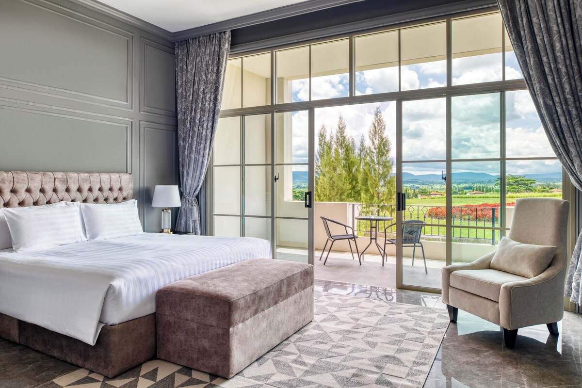 Une chambre avec un grand lit, une chaise et une vue sur l’extérieur.