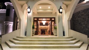 A grand entrance with a series of steps leading to a door, flanked by two large planters and two wall-mounted lanterns. - Mövenpick Resort Khao Yai (Pak Chong)