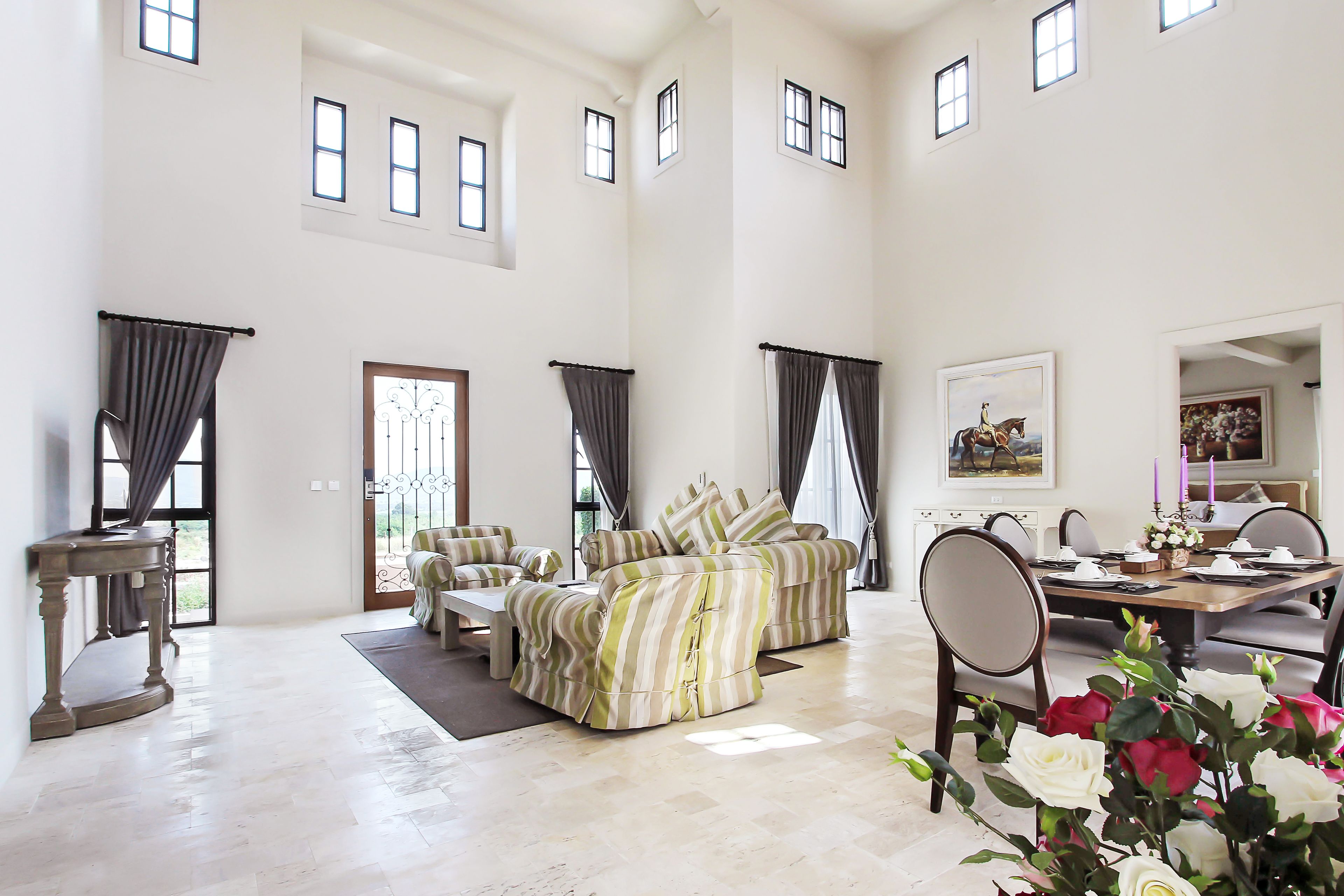 A spacious living room with high ceilings, a dining area, and a view of the outdoors.