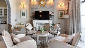 Un salon avec une cheminée, un téléviseur et deux fauteuils.