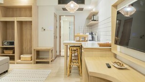 A modern kitchen with wooden cabinets, a central island, and a large window. - Amaka Bed & Breakfast (Chiang Mai)