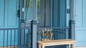 A blue door with the number 101, a wooden bench, and a chair outside a building. - Amaka Bed & Breakfast (Chiang Mai)