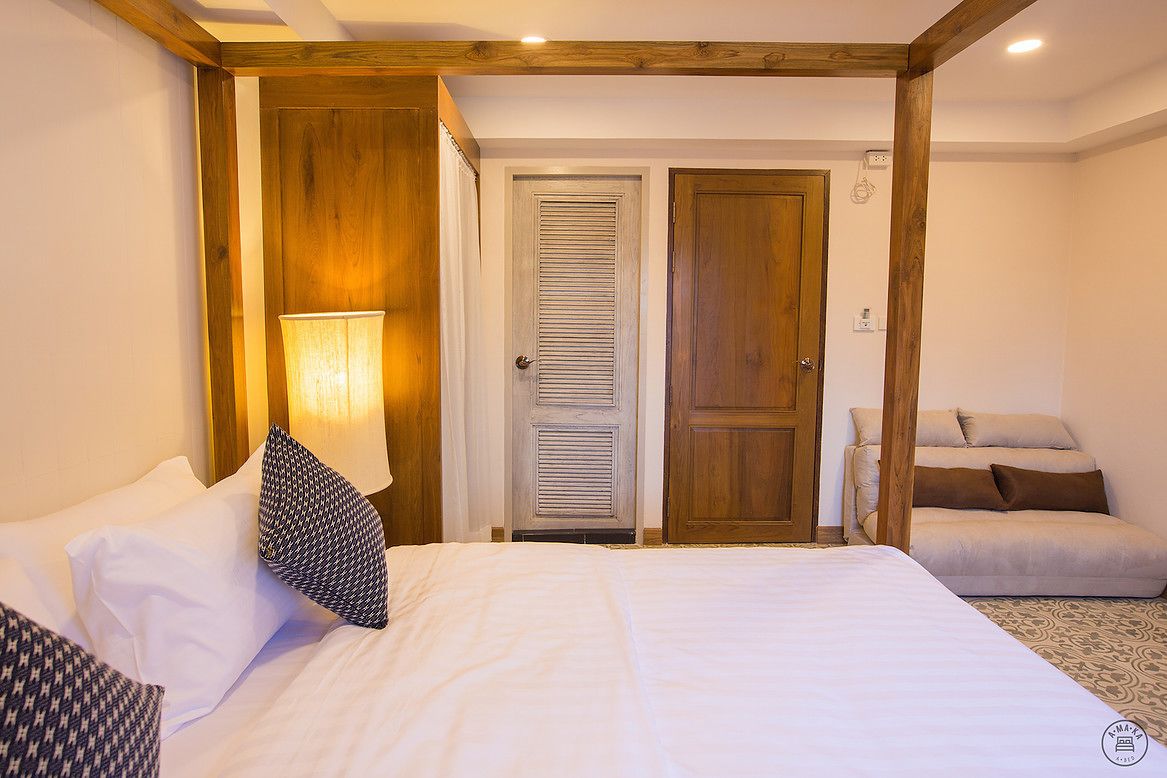 A bedroom with a bed, a nightstand, a lamp, and a door.