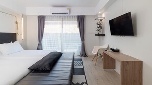 A modern hotel room with a bed, a desk, a flat-screen TV, and a window with curtains. - The Core Gallery Hotel (Chiang Mai)