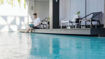 Una piscina al aire libre, sombrillas, sillones reclinables de piscina