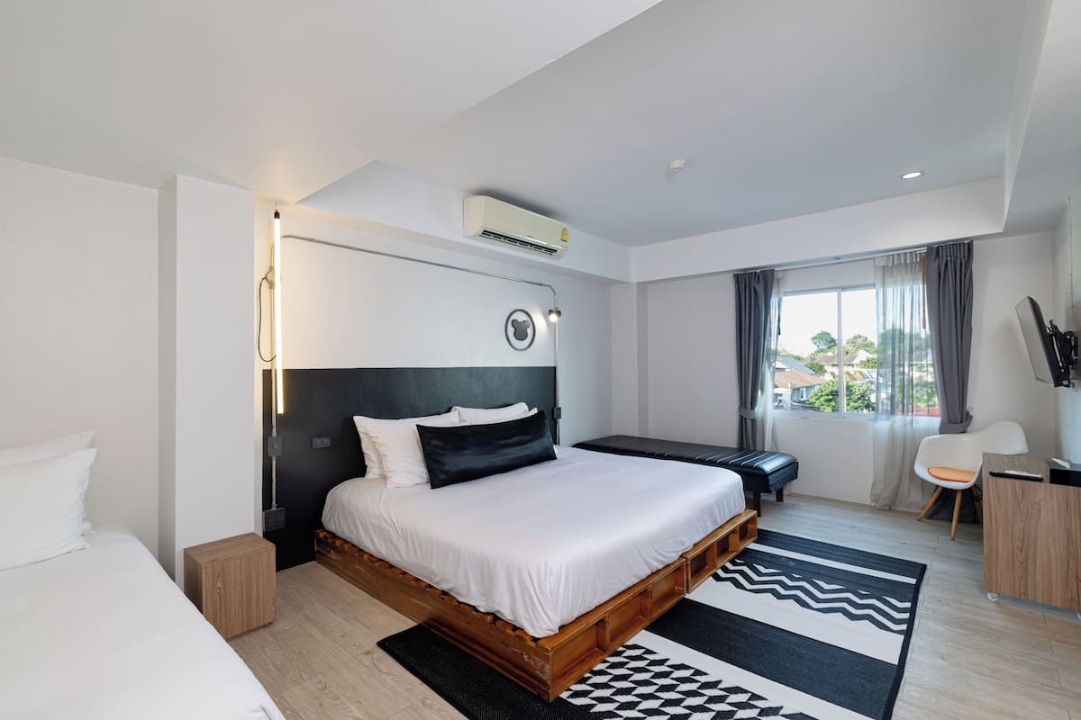 A modern hotel room with a large bed, bedside table, and a view of the outdoors.