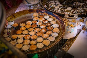 En stor metalbakke fyldt med små, runde bagværk, sandsynligvis kager, med et rustikt og patineret udseende.