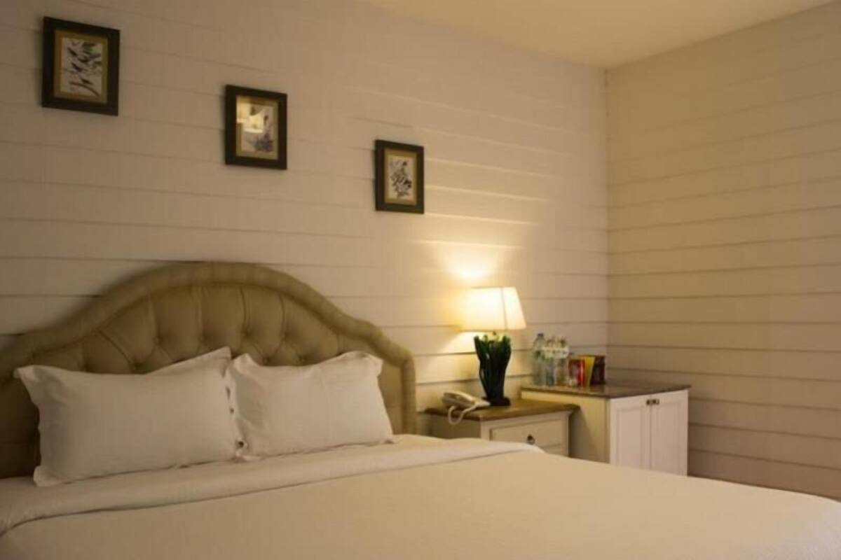 A neatly made bed with white linens, a tufted headboard, and two bedside tables with lamps and small decorative items.