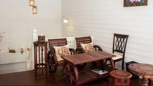 Una habitación acogedora con una mesa y sillas de madera, una mesita redonda y una lámpara fijada a la pared.