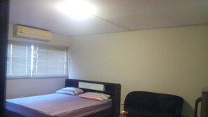 Ein kleiner, einfach eingerichteter Raum mit einem Bett, einem Sessel und einem kleinen Tisch.