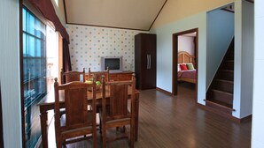 A dining area with a wooden table and chairs, a television, and a kitchen area with cabinets and a refrigerator. - Mayfair Pension (Pyeongchang)