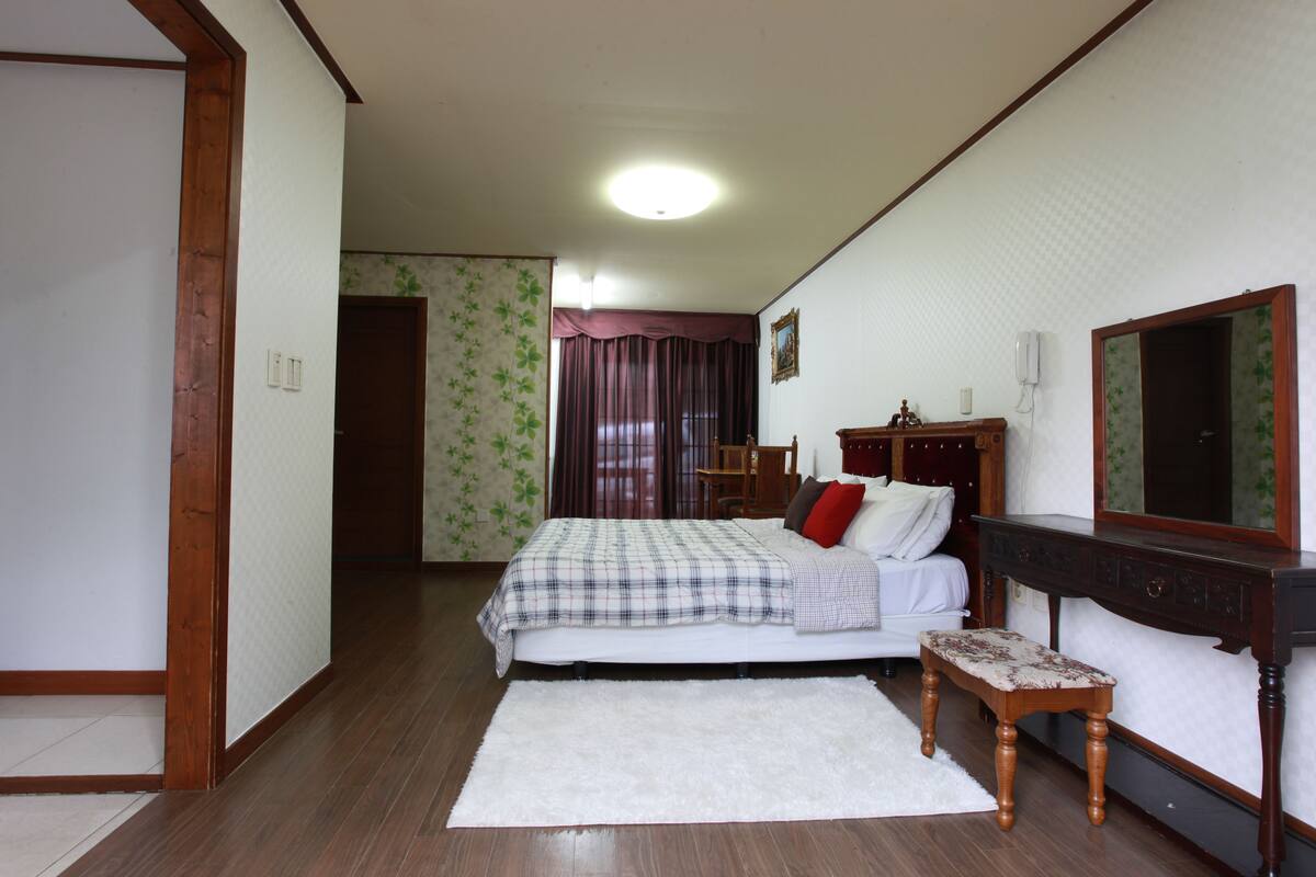 A bedroom with a bed, bedside table, and a mirror.