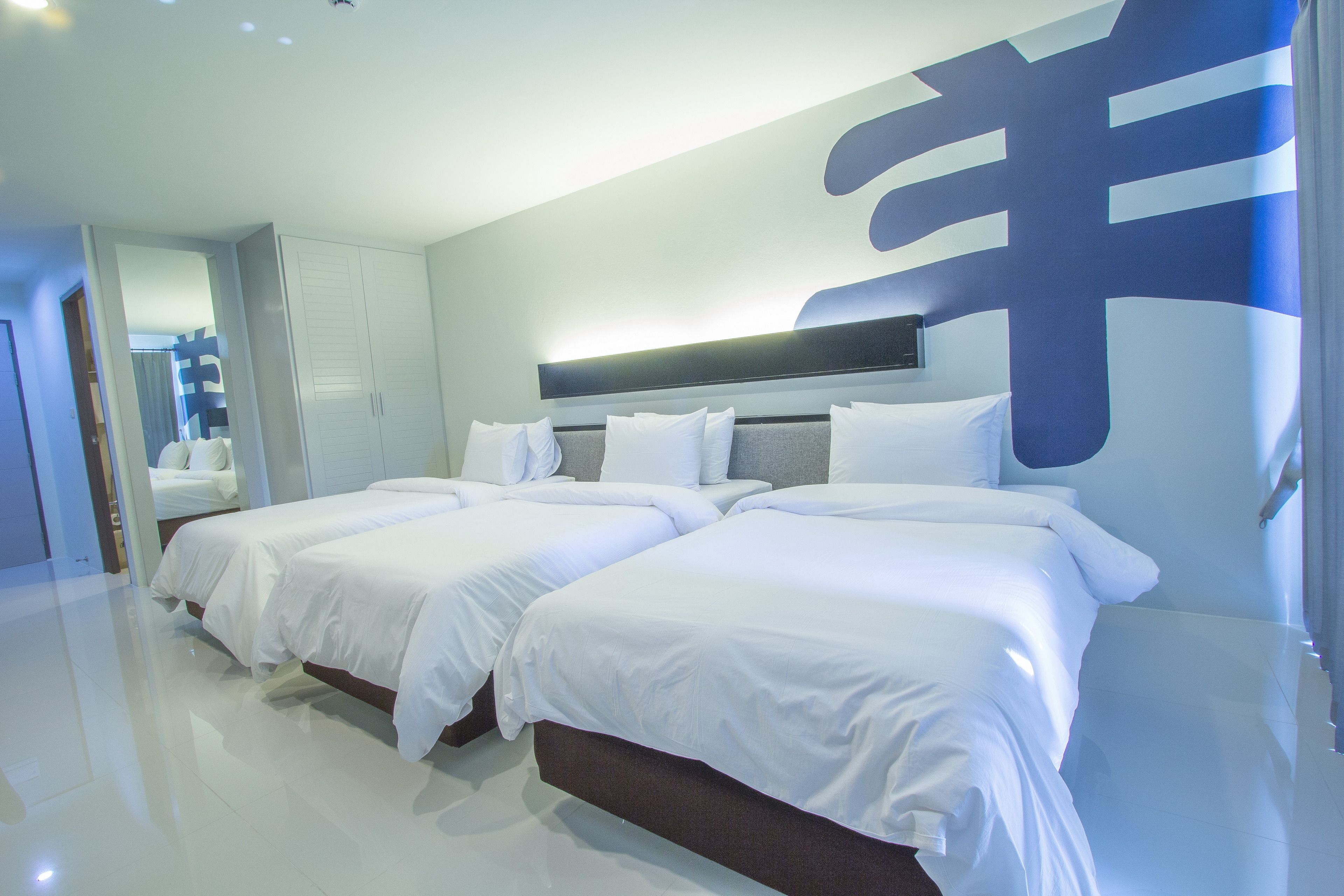Una camera d'albergo moderna con due letti, un'ampia opera d'arte astratta al muro e un design luminoso e pulito.