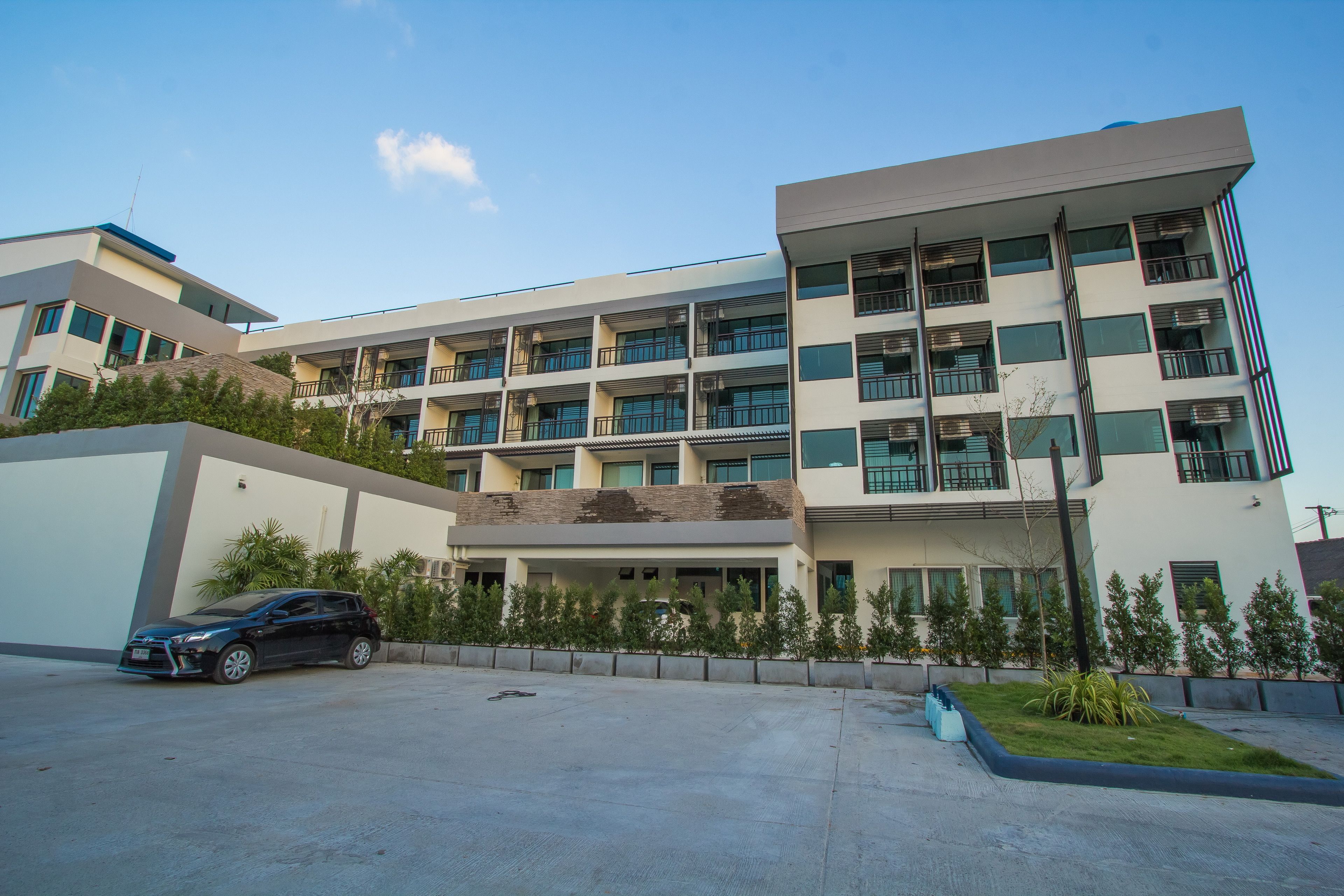 A modern multi-story building with a parking area in front.