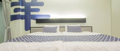 A hotel room with a large bed, a headboard with a light fixture, and a wall with a large decorative pattern.