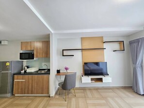 Une cuisine moderne avec des meubles en bois, un four à micro-ondes encastré et un réfrigérateur en acier inoxydable.