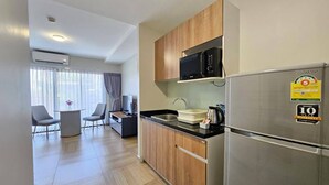 A modern kitchen with a microwave, a kettle, and a refrigerator. There is a dining area with a table and chairs. - Chiva Bangkok Hotel (Bangkok)