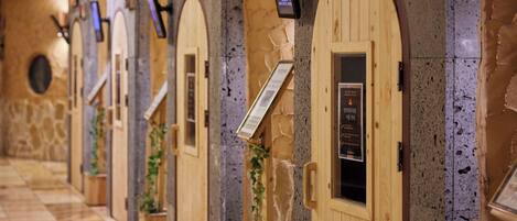 A row of wooden spa rooms with arched doorways and stone walls.