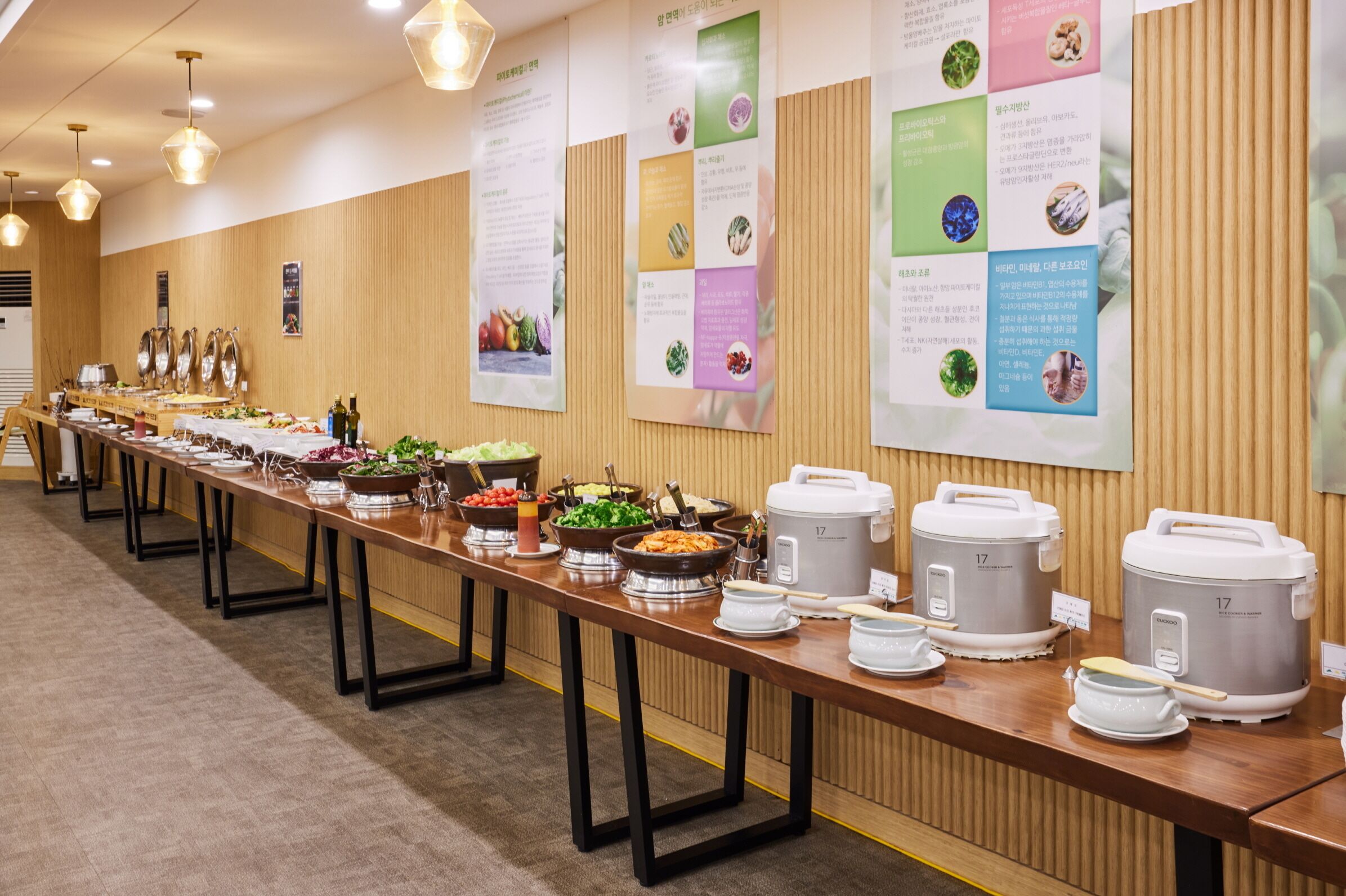 Montaje de bufé con varias estaciones de comida, incluyendo platos calientes y fríos, dispuesto sobre una mesa larga.