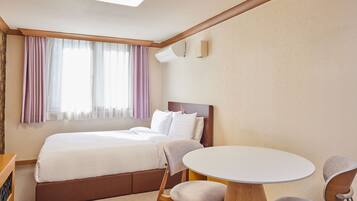 Una habitación de hotel con una cama, una mesita redonda y una silla.