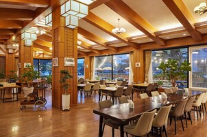Un comedor amplio con vigas de madera, ventanas grandes y varias mesas y sillas.