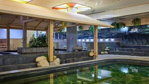 Ein Wellnessbereich mit Pool, Holzmöbeln und einer Felswand im Hintergrund.