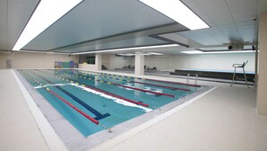 Ein Hallenbad mit mehreren Bahnen, Deckenbeleuchtung und Fliesenboden.