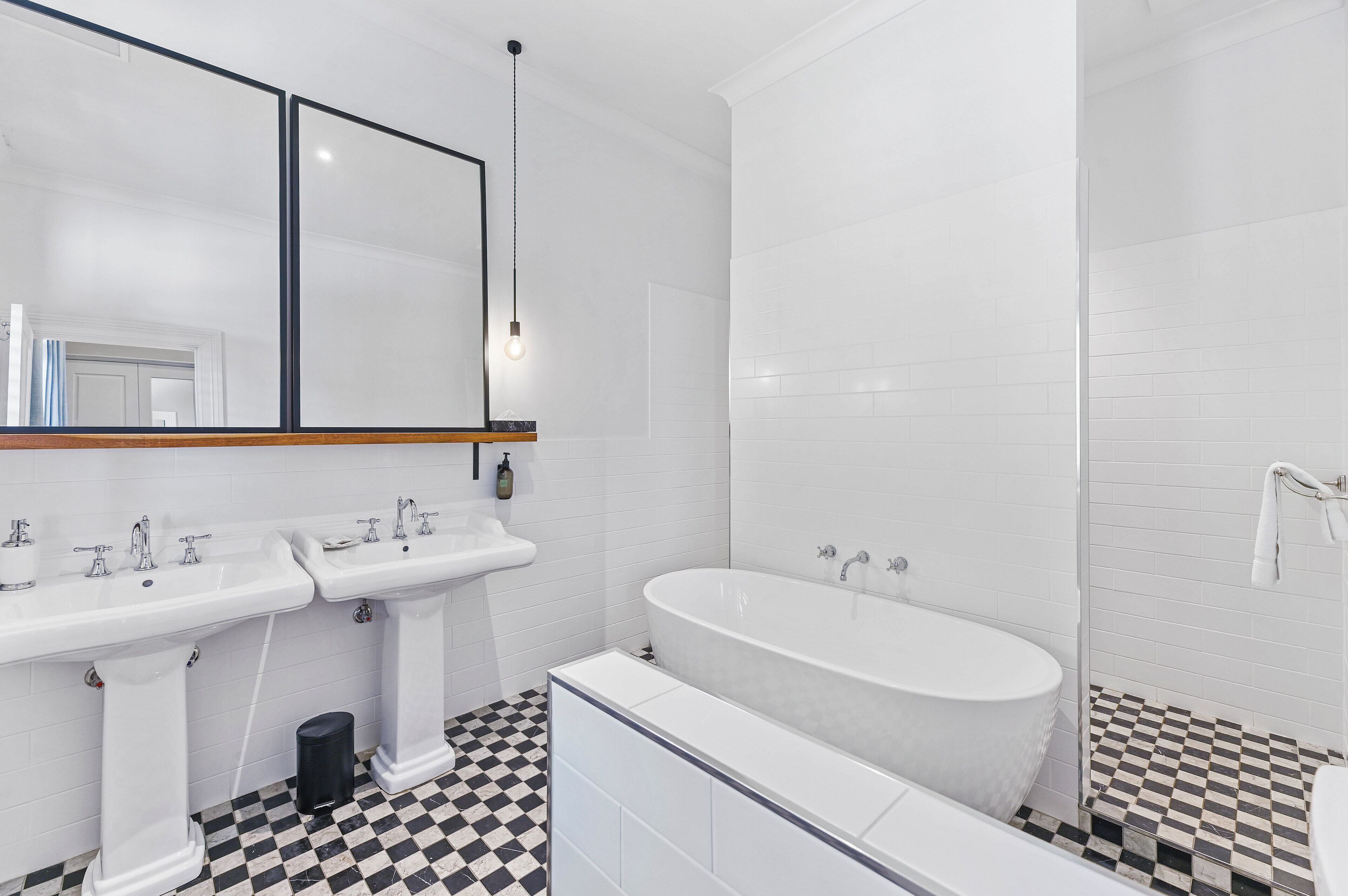 Un baño moderno con dos lavamanos, una bañera y un espejo grande.